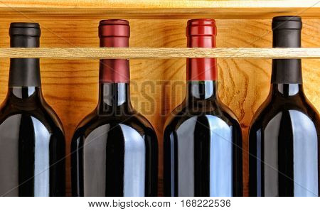 Four red wine bottles in a wooden case. Closeup filling the frame.