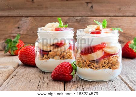 Healthy Strawberry And Banana Parfaits In Mason Jars With A Rustic Wood Background