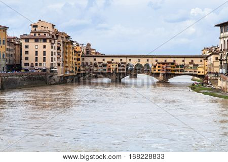 travel to Italy - dirty water of Arno river and view of Ponte Vecchio (Old Bridge) in Florence city in autumn