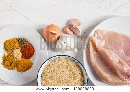 Ingredients for chicken curry: raw meat uncooked rice various spices top view copy space for text selective focus