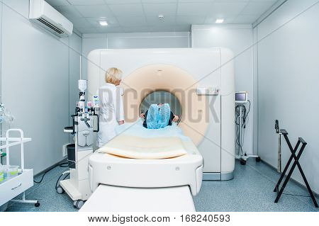 Female Doctor Adjusts Computed Tomography Or Computed Axial Tomography Scan Machine With Lying Patie