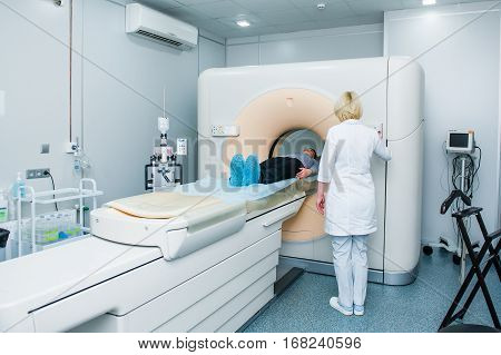 Female Doctor Adjusts Computed Tomography Or Computed Axial Tomography Scan Machine With Lying Patie