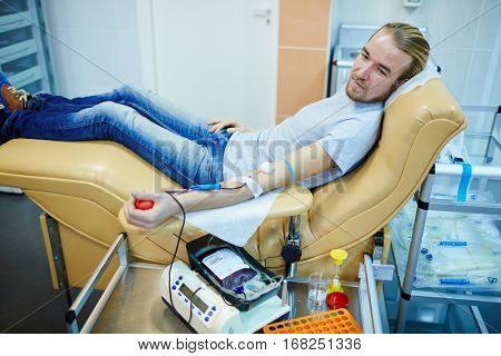 Young selfless man transfusing his blood in center of voluntary blood-drive