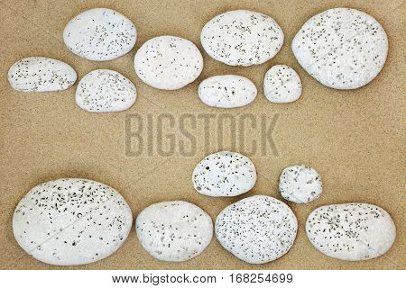Abstract beach background on sand with white stones with bore holes made by bivalve molluscs.