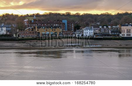 Rowers on the River Thames. Shot shows the rowers getting ready to take the boats out onto the Thames at low tide on a bright weekend morning.