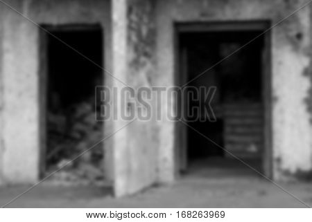 Blurred black and white background. The entrance of an abandoned house. A pile of debris inside the building.