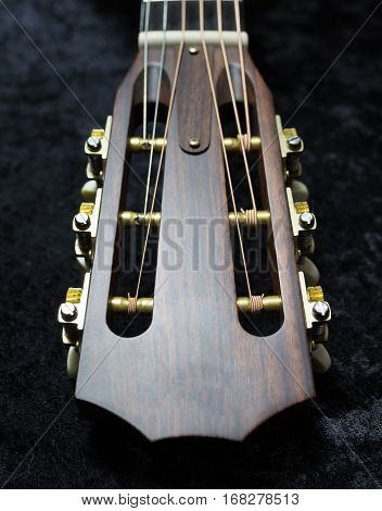 Acoustic guitar's headstock on a black background