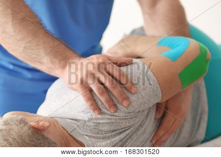 Physiotherapist working with elderly patient in clinic, closeup
