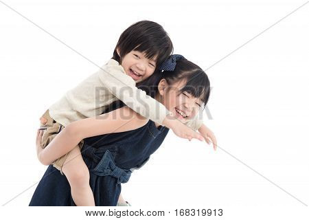 Asian girl giving her brother piggyback ride on white background isolated
