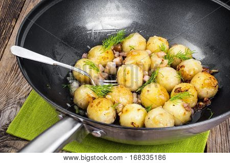 Fried potato dumplings with bacon in frying pan. Studio Photo