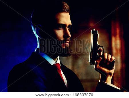 Danger man with gun looking aside portrait. Contrast dramatic red and blue colors