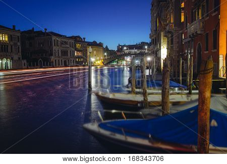 Grand canal in Venice during night with parked boats and light traces of the transport