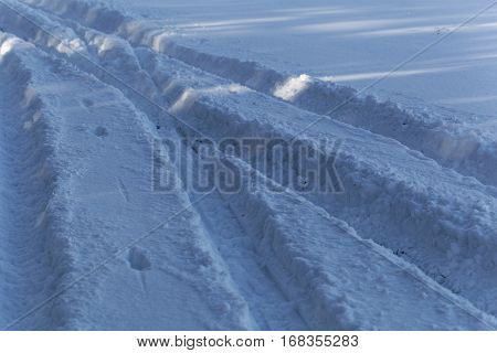 Fresh car traces on a snow covered surface.
