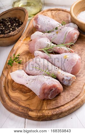 Raw chicken drumsticks on cutting board. Uncooked chicken legs.