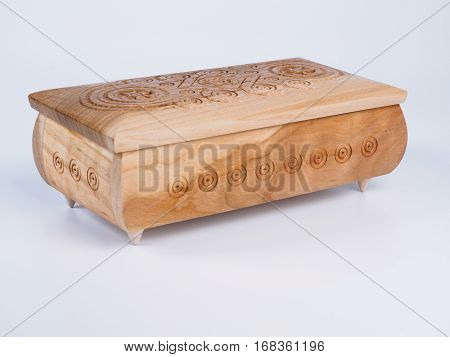 Picture of the carved wooden jewel-box for bijouterie on isolated white background. Carved pattern on a jewel box. Closed box made of light wood. Side view.