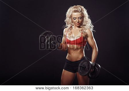 athletic young blonde curl girl doing a fitness workout with dumbbells on black background isolated