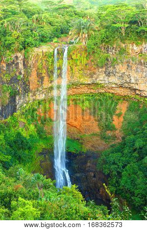 Beautiful waterfall in green rainforest. Scenery from Chamarel waterfall on the River du Cap in jungle. The water falls by 95 metres along a vertical cliff. Mauritius one part of The Mascarene Islands