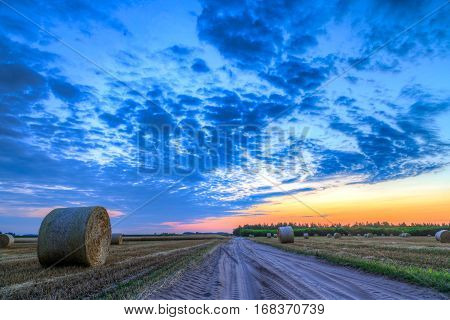 Sunset over rural road and farm field with hay bales-This photo make HDR