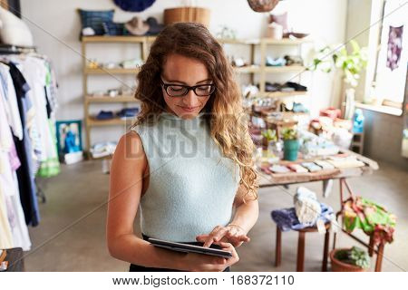 Female business owner using tablet computer in clothes shop
