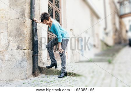 Senior walking through city, suffering from knee pain