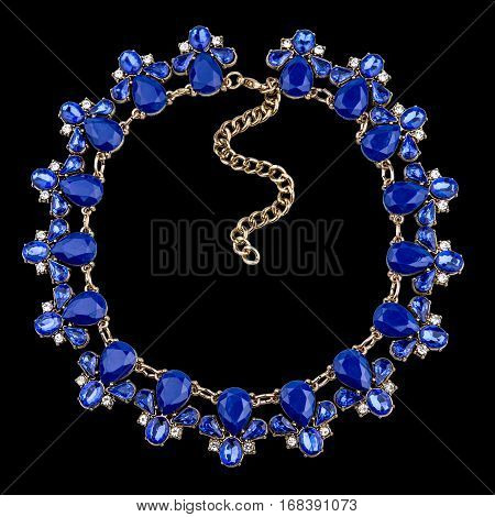 Golden necklace with sapphire on black background
