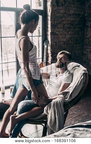 Love and passion. Attractive young woman flirting with her boyfriend while standing in front of him at home