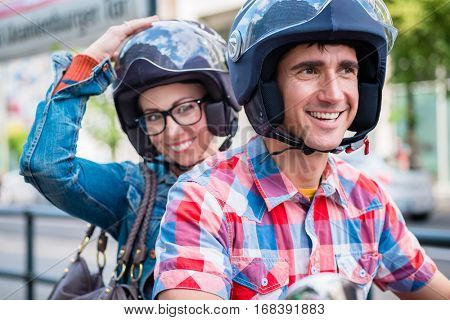 Smiling girl with glasses sitting on pillion seat of scooter