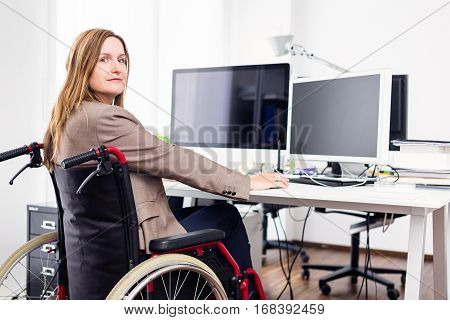 a woman sitting in a wheelchair is working in a modern office