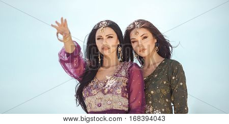 Adventure of two sisters princesses happy standing in the desert and looking at landscape. Two beautiful mixed race asian caucasianl girls enjoy a joint journey. Creative art fashion po rtrait shot of two gorgeous attractive models outdoor