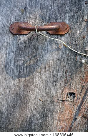 Old plywood door with a dead lock and the rusty door handle.