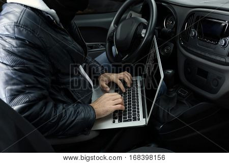 Car thief hacking security systems with laptop computer