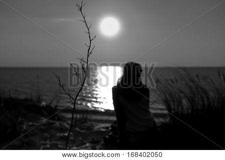Black the white photo of a sunset at the sea with a silhouette of the person