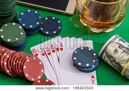 from 10 to Ace heart straight flush on poker and casino chips money on green table