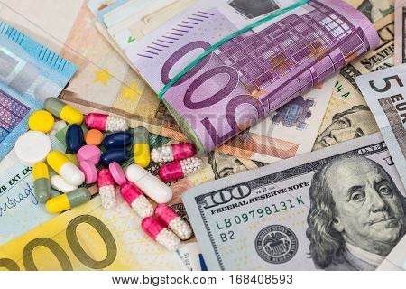 macro pills and tablets on euro and dollar banknotes for background.