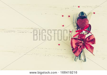 Valentine's Day tabble setting with cutlery on white shabby chic background. Valentine's Day place setting cutlery on white wooden background. Romantic love Valentines concept. Copy space. Top view.