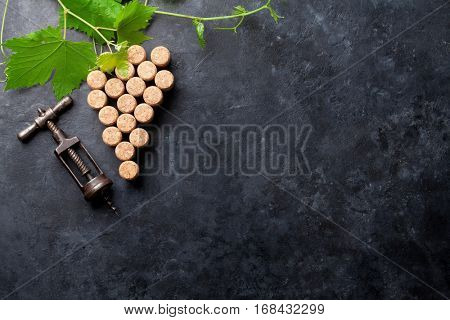 Wine corks grape shape, corkscrew and vine on stone table. Top view with copy space for your text