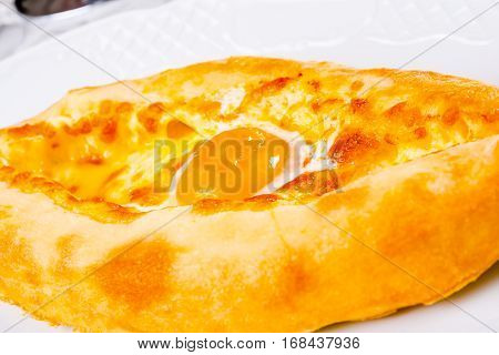 Ajarian khachapuri with yolk on white plate