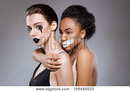 I got your back. Pretty magnificent professional models demonstrating strong bond of black and white while working on the art project and posing in a studio