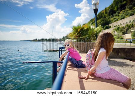 Two Cute Little Sisters Having Fun On A Shore Of Lake Garda In Toscolano-maderno, A Small Town And C