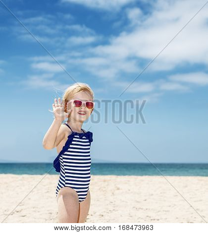 Happy Girl In Striped Swimsuit On A White Beach Handwaving