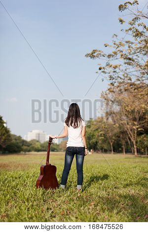 Musician and her guitar in a park away form town