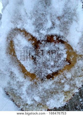 Drawing hearts in the snow. Snow heart shape. Heart on the snow closeup.