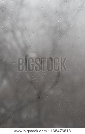 Heart of glass with rain drops on a gray sky background