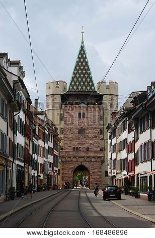 Basel, Switzerland - July 12, 2014. View of Spalentor gate on Spalenvorstadt street in Basel, with historic buildings, tram tracks, commercial properties and people.