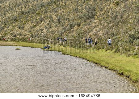 COTOPAXI, ECUADOR, FEBRUARY - 2016 - Group of people trekking a trail over lake at Cotopaxi national park Ecuador