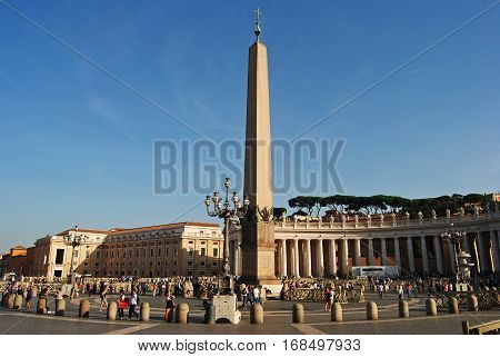 Vatican, Vatican - October 10, 2014. The 25m obelisk at St Peters Square in Vatican, with surrounding buildings and people, at dusk.