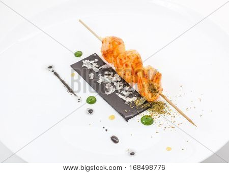 Pieces of meat on skewer with greens and sauces