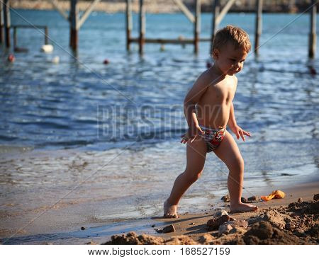 DIDIM TURKEY - JULY 9 2014. Baby boy playing with toys on the sea.