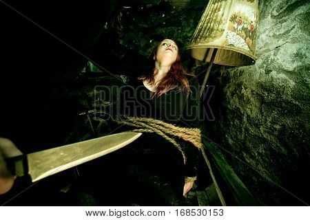 young woman tied to a chair in a dirty cellar