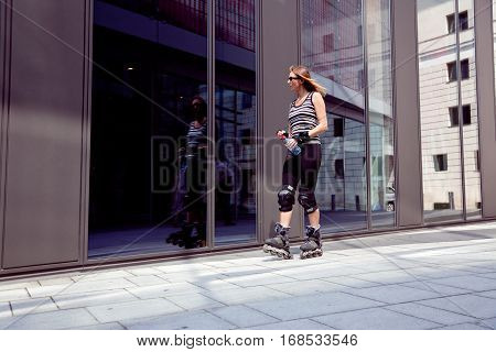 a woman in her 40s is rollerblading in the city, looking at shop windows